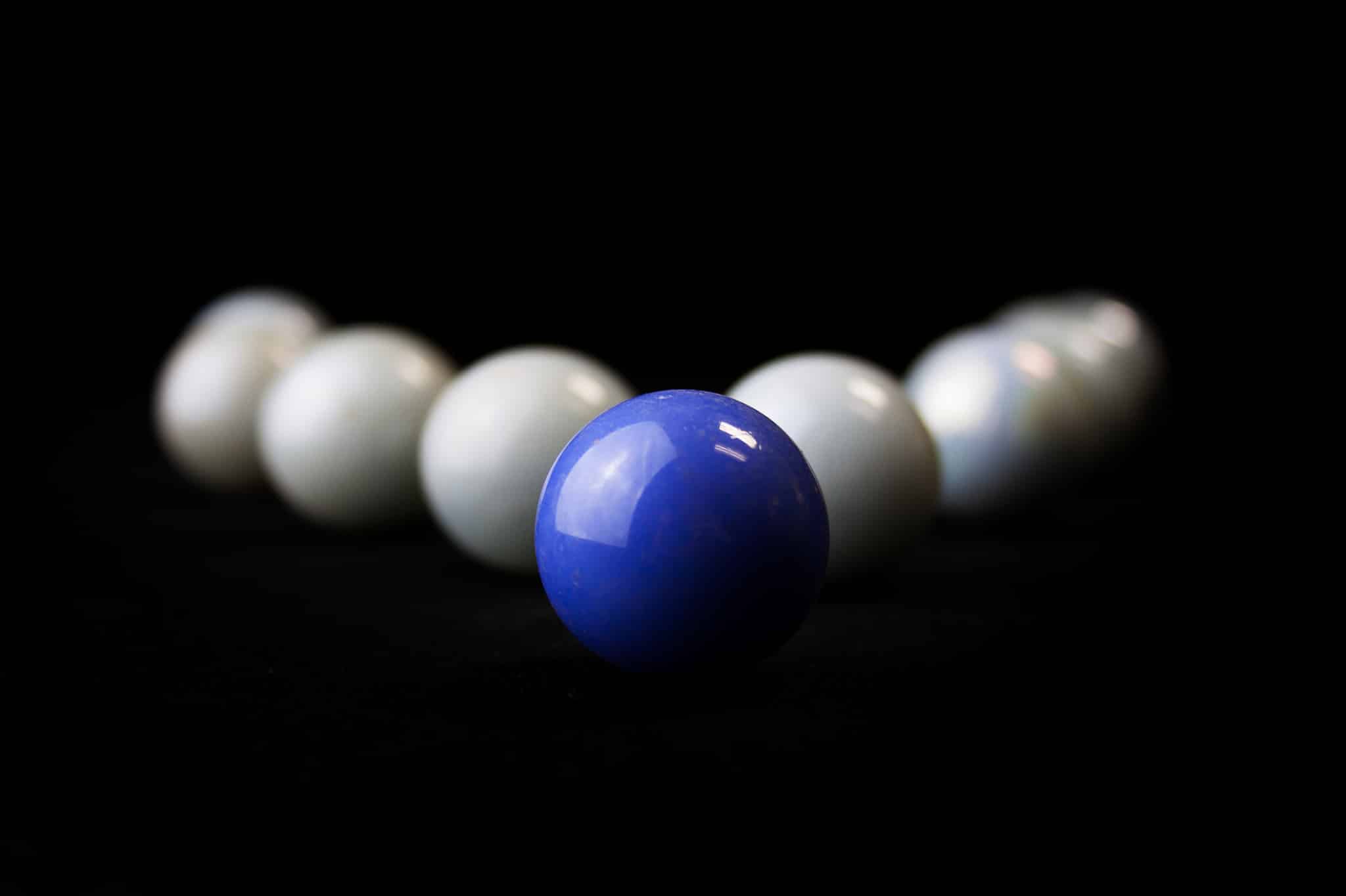 string of white marbles with 1 blue in the front