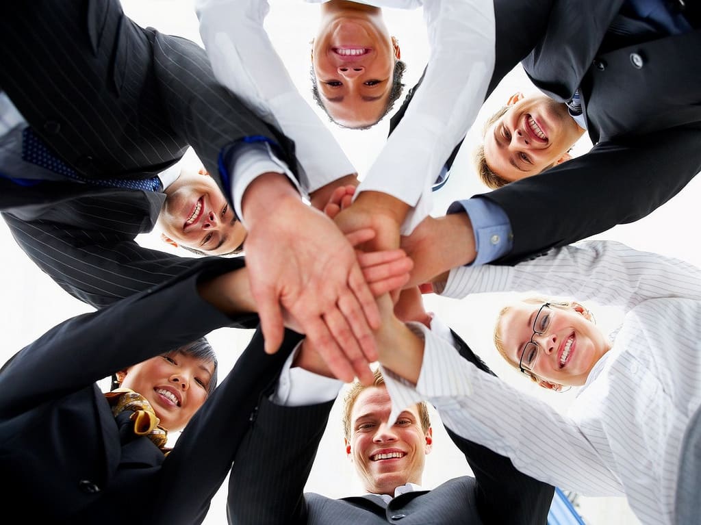 photo of people with hands together, being a team